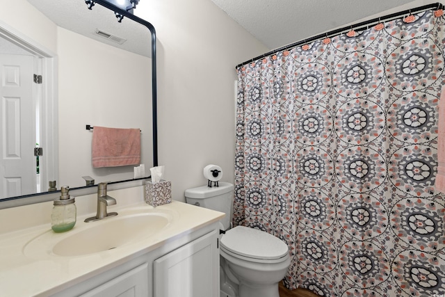 bathroom with toilet, visible vents, a textured ceiling, and vanity