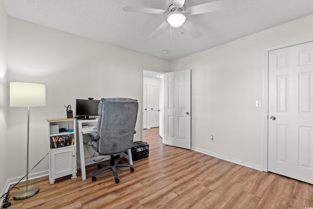 office space with a textured ceiling, baseboards, a ceiling fan, and light wood-style floors