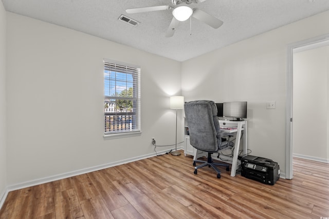 unfurnished office featuring baseboards, visible vents, a textured ceiling, and light wood finished floors