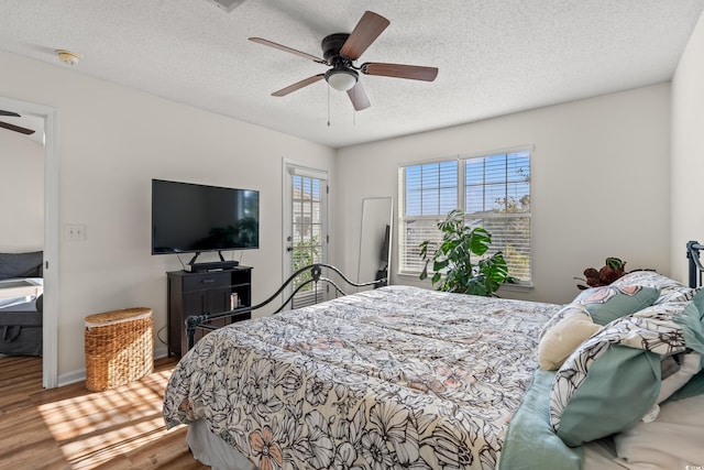 bedroom featuring baseboards, a ceiling fan, wood finished floors, access to outside, and a textured ceiling