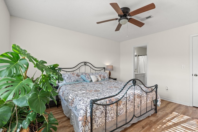 bedroom with ceiling fan, wood finished floors, visible vents, and baseboards