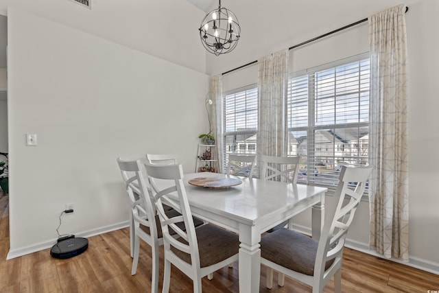 dining space with an inviting chandelier, baseboards, and wood finished floors