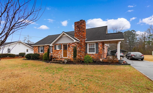 view of front of house featuring brick siding, a chimney, and a front yard