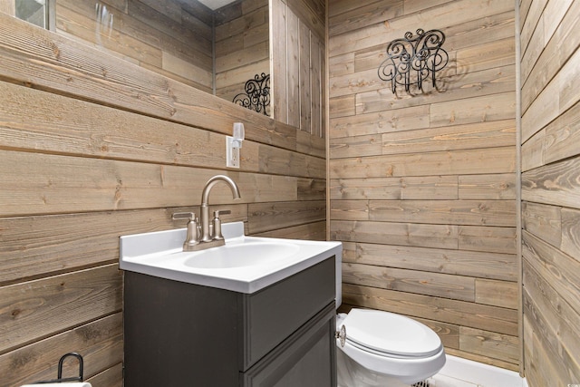 half bath with vanity, toilet, and wood walls