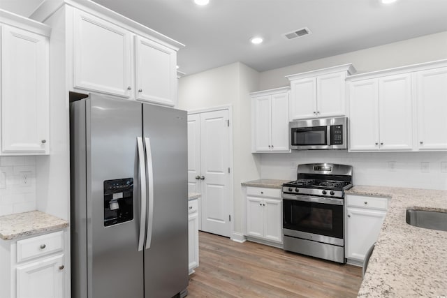 1043 Harbison Cir, Myrtle Beach, SC 29579 - kitchen featuring stainless steel appliances, white cabinetry, decorative backsplash, light wood-style floors, and recessed lighting