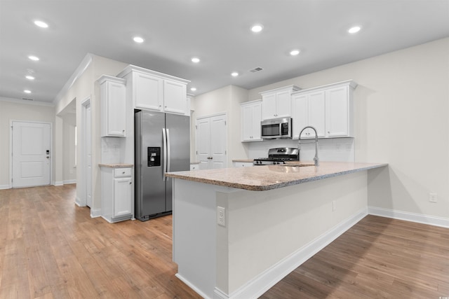 1043 Harbison Cir, Myrtle Beach, SC 29579 - kitchen with stainless steel appliances, a sink, light wood-style flooring, white cabinets, and baseboards