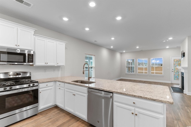 1043 Harbison Cir, Myrtle Beach, SC 29579 - kitchen with appliances with stainless steel finishes, a sink, a peninsula, light wood finished floors, and white cabinetry