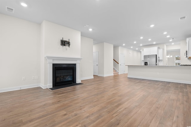 1043 Harbison Cir, Myrtle Beach, SC 29579 - unfurnished living room with light wood-style flooring, a fireplace with flush hearth, stairway, recessed lighting, and baseboards