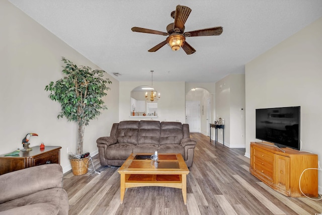 living area featuring arched walkways, a textured ceiling, and wood finished floors