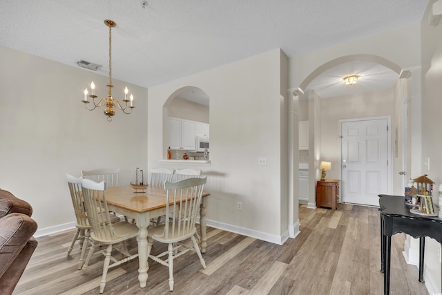 dining space with visible vents, baseboards, a textured ceiling, and light wood-type flooring