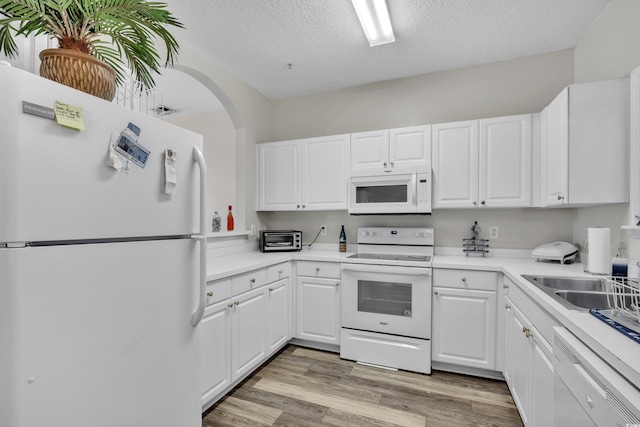 kitchen featuring light countertops, white cabinets, white appliances, a textured ceiling, and light wood-type flooring