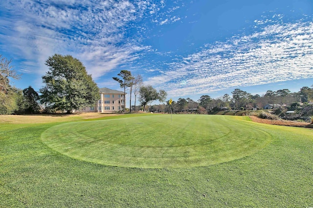 view of property's community featuring view of golf course and a lawn