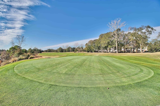 view of community with view of golf course and a yard