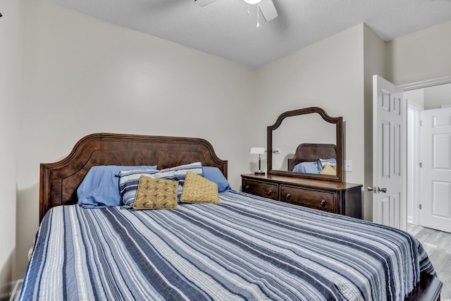 bedroom with a ceiling fan, a textured ceiling, and light wood-type flooring