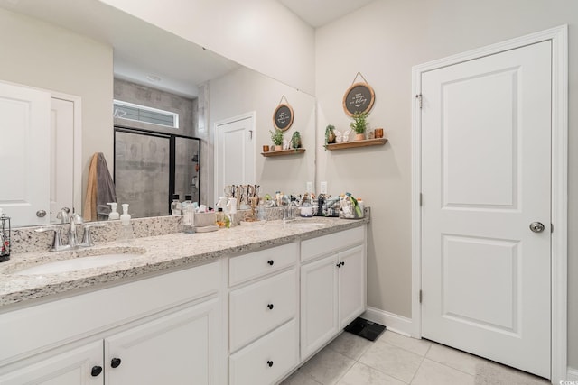 full bath with double vanity, a shower stall, baseboards, and a sink