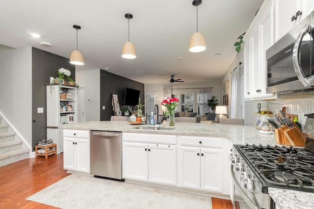 kitchen with stainless steel appliances, pendant lighting, white cabinets, and a sink