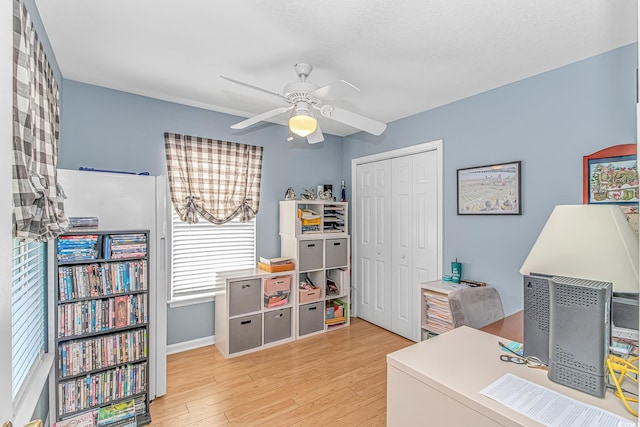 office with light wood-type flooring and ceiling fan