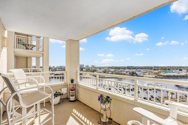 balcony with a water view, a sunroom, and a city view