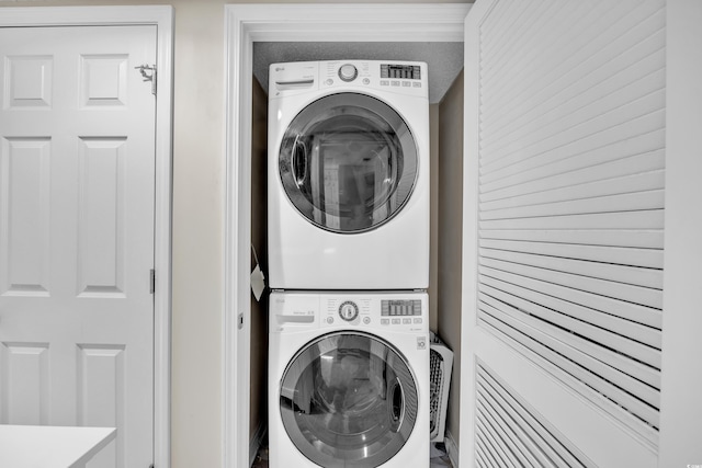 clothes washing area featuring stacked washer and dryer and laundry area