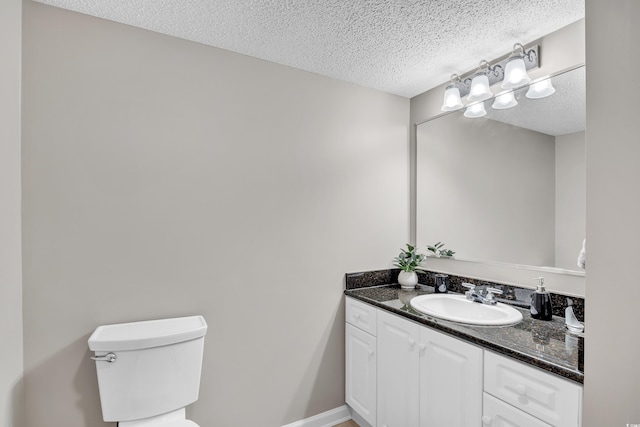 bathroom featuring a textured ceiling, vanity, toilet, and baseboards