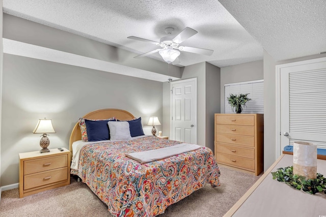 bedroom with baseboards, a ceiling fan, a textured ceiling, and light colored carpet