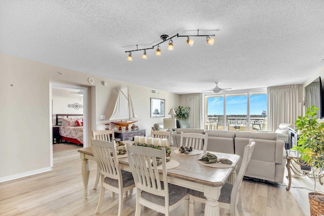 dining space featuring a textured ceiling, light wood finished floors, a ceiling fan, and baseboards