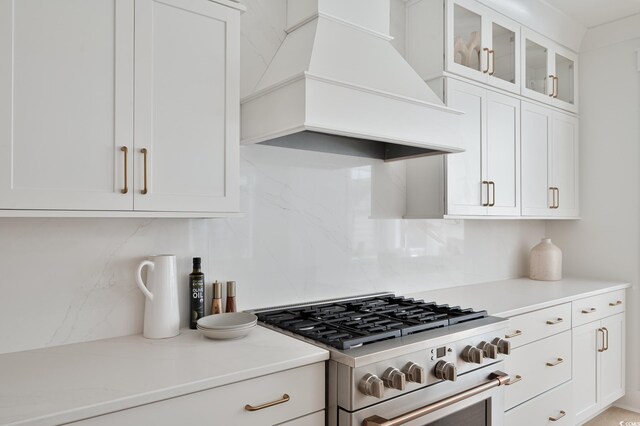 1328 Foxtail Dr, Longs, SC 29568 - kitchen with stainless steel gas range, custom range hood, tasteful backsplash, light countertops, and white cabinets