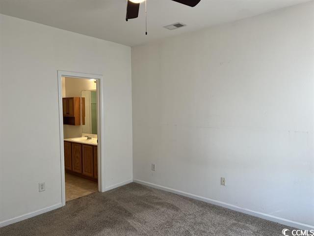 unfurnished bedroom with ensuite bathroom, carpet, visible vents, and baseboards