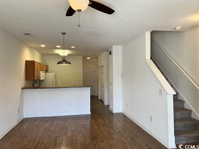 kitchen with white appliances, dark wood-type flooring, visible vents, dark countertops, and pendant lighting