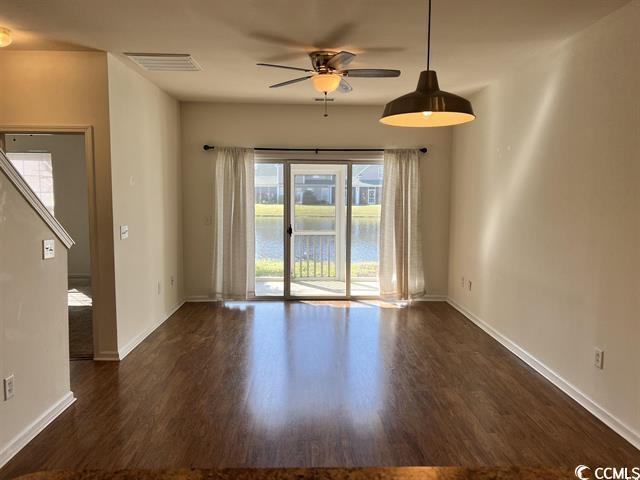 unfurnished living room with a ceiling fan, dark wood finished floors, visible vents, and baseboards