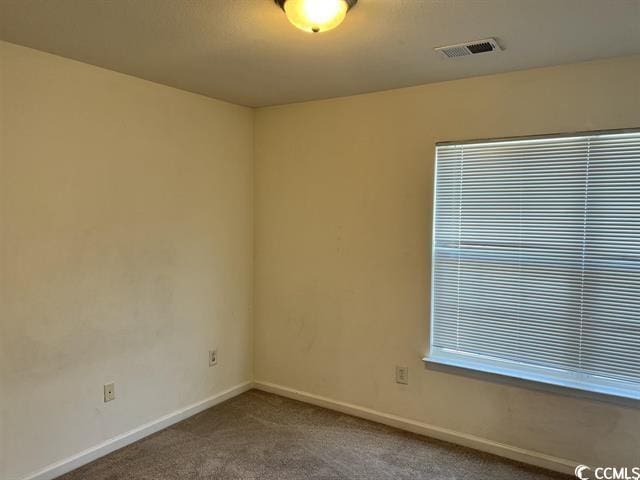 carpeted spare room featuring visible vents and baseboards