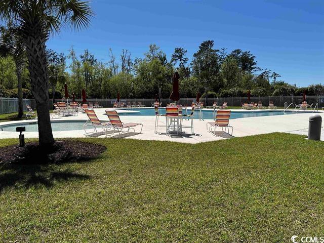 community pool with a lawn, a patio, and fence