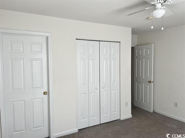 unfurnished bedroom featuring a ceiling fan, dark colored carpet, a closet, and baseboards