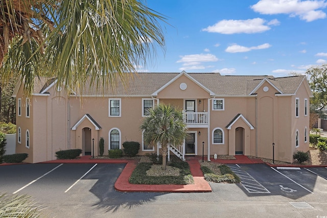 view of property featuring stucco siding, a balcony, and uncovered parking