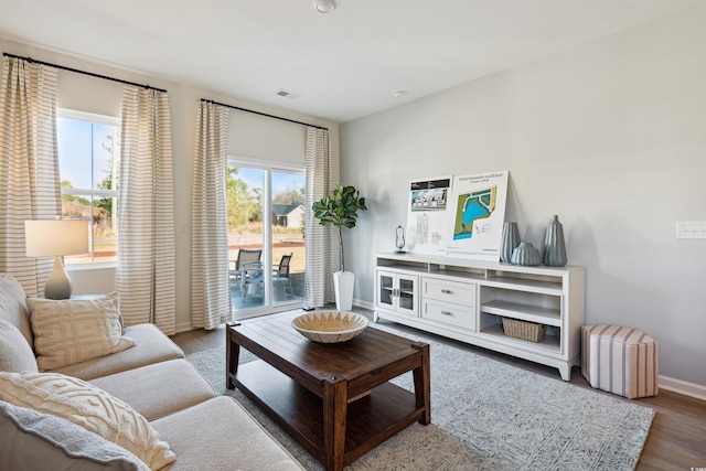 living room with wood finished floors, visible vents, and baseboards