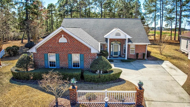 traditional-style house featuring roof with shingles, concrete driveway, and brick siding