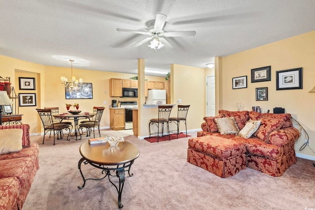 living area with light carpet, baseboards, a textured ceiling, and ceiling fan with notable chandelier