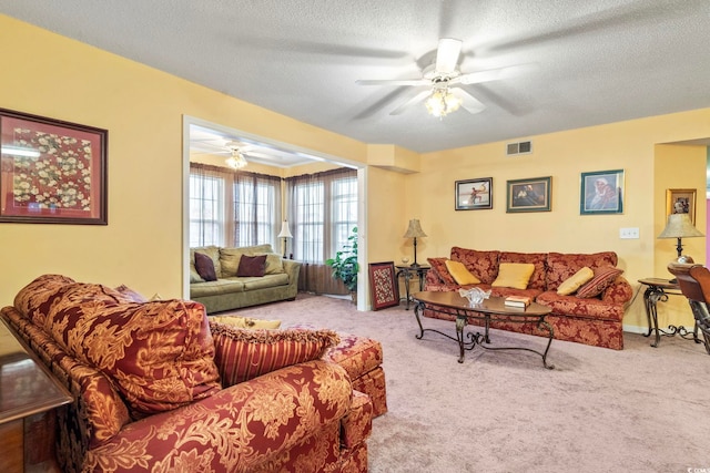 living room featuring light carpet, ceiling fan, a textured ceiling, and visible vents