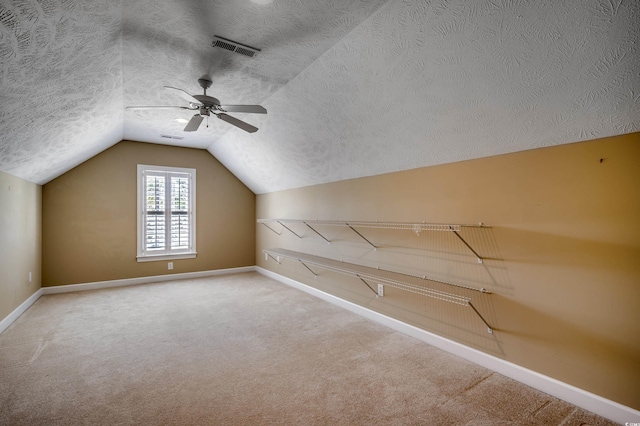 additional living space with carpet, lofted ceiling, visible vents, a textured ceiling, and baseboards