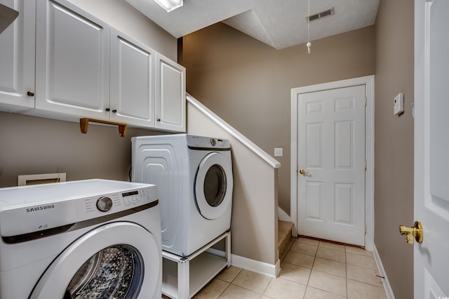 washroom featuring cabinet space, light tile patterned floors, baseboards, visible vents, and independent washer and dryer