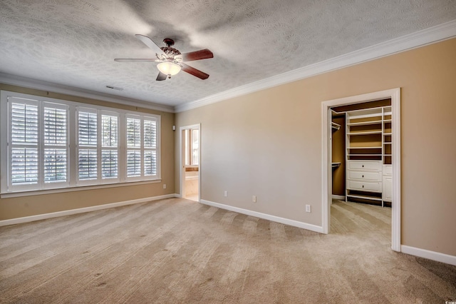 interior space with light colored carpet, ornamental molding, a ceiling fan, a textured ceiling, and baseboards