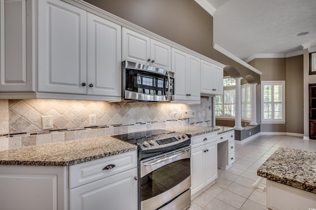 kitchen featuring light tile patterned flooring, crown molding, appliances with stainless steel finishes, light stone countertops, and ornate columns