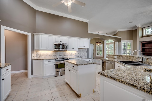 kitchen featuring crown molding, stainless steel appliances, a sink, and a center island