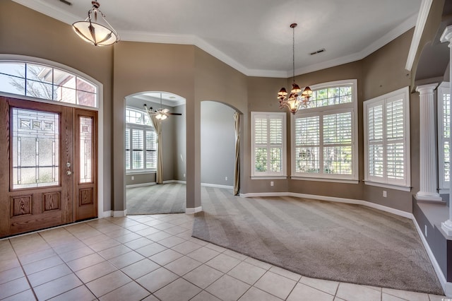 carpeted foyer entrance with visible vents, arched walkways, tile patterned floors, crown molding, and ornate columns