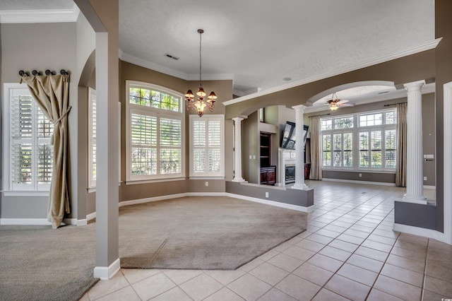 interior space featuring light carpet, light tile patterned floors, decorative columns, a glass covered fireplace, and ceiling fan with notable chandelier