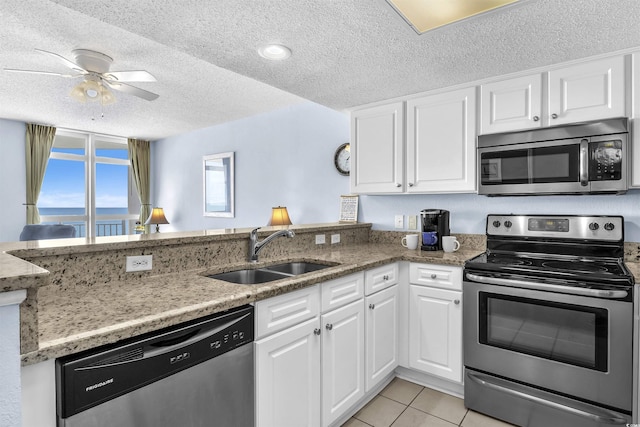 kitchen featuring white cabinets, stainless steel appliances, a sink, a peninsula, and a textured ceiling