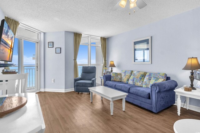 living area featuring ceiling fan, baseboards, wood finished floors, and a textured ceiling