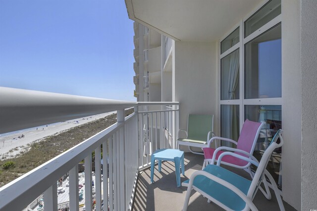 balcony featuring a view of the beach and a water view
