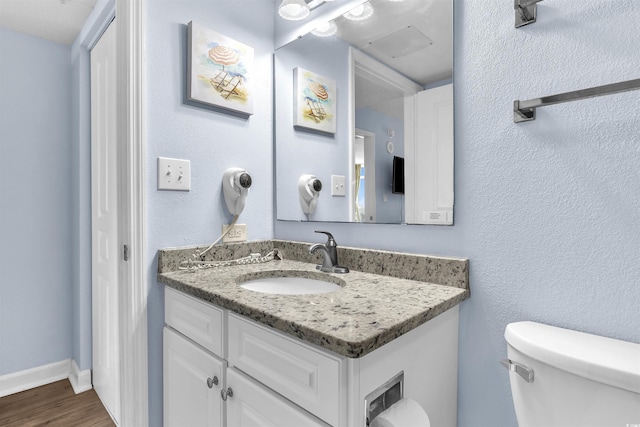 bathroom featuring toilet, vanity, and wood finished floors