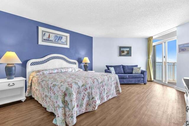 bedroom featuring wood finished floors, a textured ceiling, and access to outside